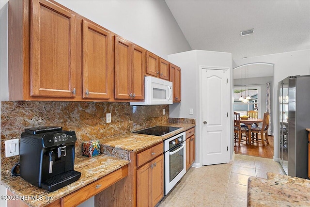 kitchen featuring tasteful backsplash, stainless steel appliances, light stone countertops, and light tile patterned floors