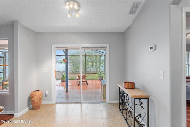 entryway with a textured ceiling and light tile patterned floors