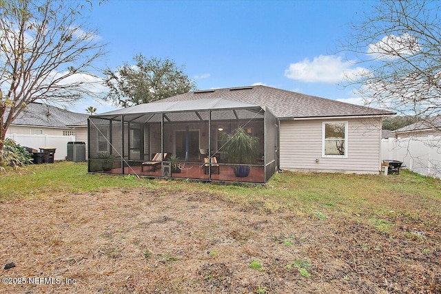 rear view of property with central AC, a yard, and glass enclosure