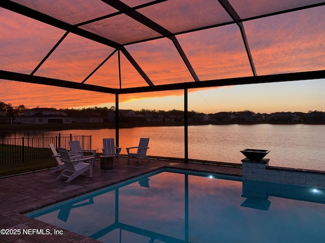 pool at dusk with a patio, a lanai, and a water view