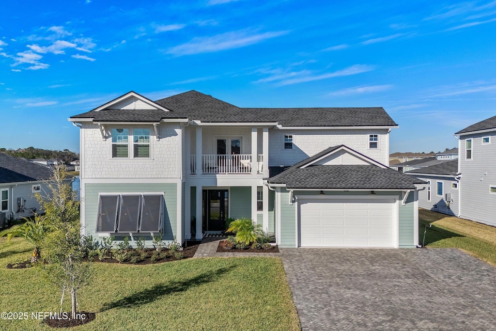 front of property with a garage, a balcony, and a front yard