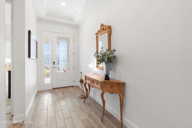 entryway featuring a raised ceiling and ornamental molding