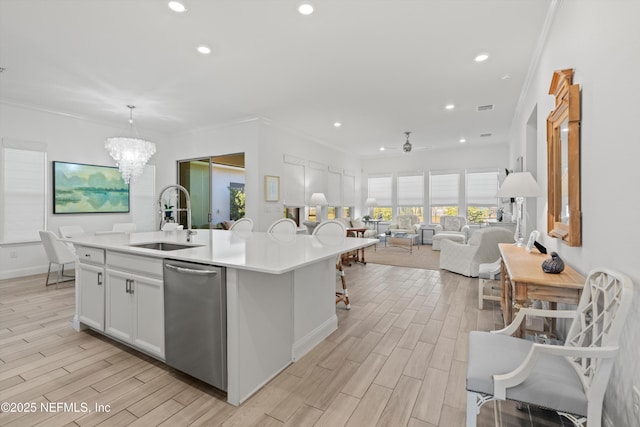 kitchen featuring white cabinets, an island with sink, pendant lighting, sink, and ceiling fan with notable chandelier