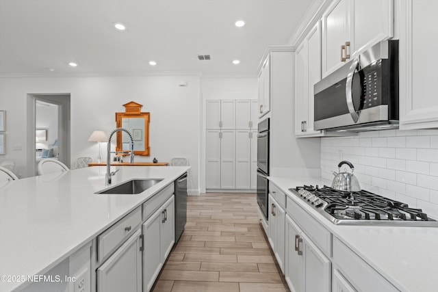 kitchen featuring sink, stainless steel appliances, white cabinetry, and ornamental molding