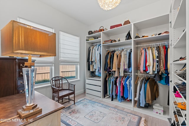 walk in closet featuring a notable chandelier and light wood-type flooring