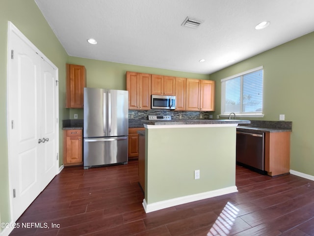 kitchen featuring backsplash, dark hardwood / wood-style floors, a kitchen island, and stainless steel appliances