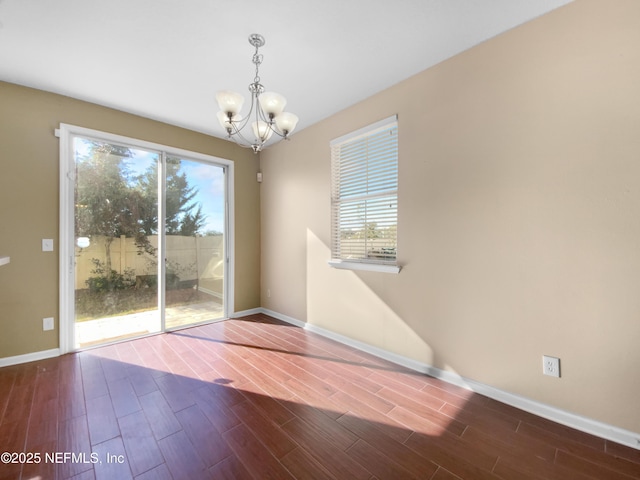 spare room featuring dark hardwood / wood-style flooring and a chandelier