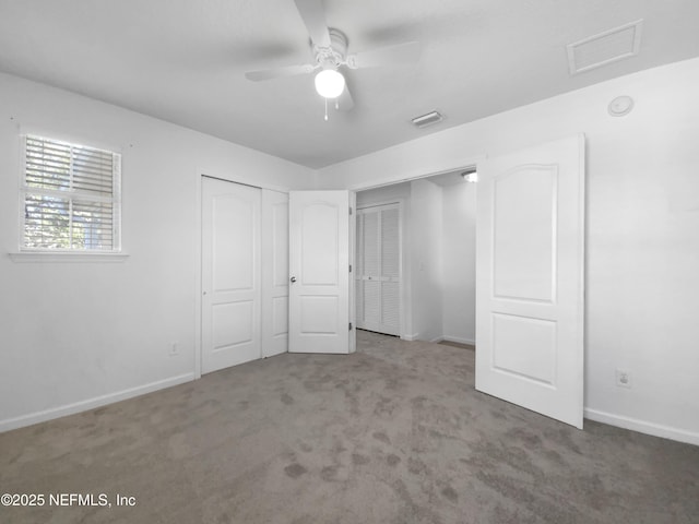 unfurnished bedroom featuring carpet flooring, ceiling fan, and two closets