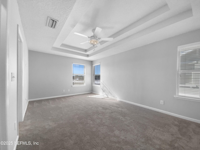 carpeted spare room featuring a tray ceiling, ceiling fan, and a textured ceiling