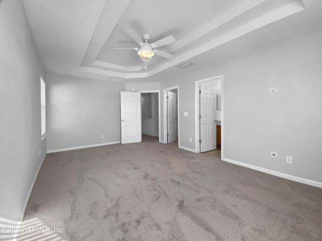 unfurnished bedroom with a raised ceiling, ceiling fan, and carpet