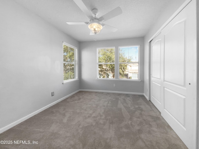 unfurnished bedroom featuring carpet flooring, a textured ceiling, a closet, and ceiling fan