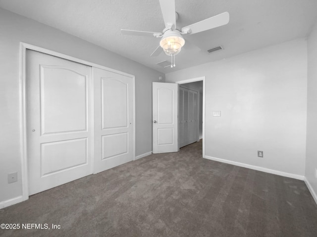 unfurnished bedroom featuring ceiling fan, a closet, dark carpet, and a textured ceiling