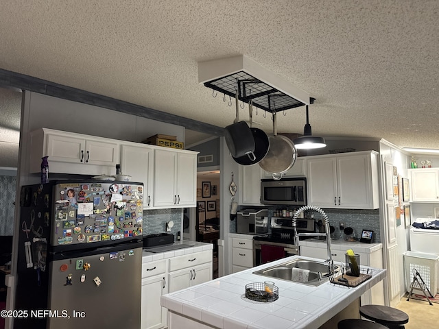 kitchen featuring tile counters, white cabinetry, backsplash, and appliances with stainless steel finishes