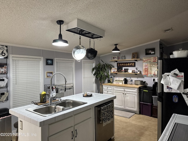 kitchen featuring appliances with stainless steel finishes, sink, tile counters, white cabinets, and hanging light fixtures