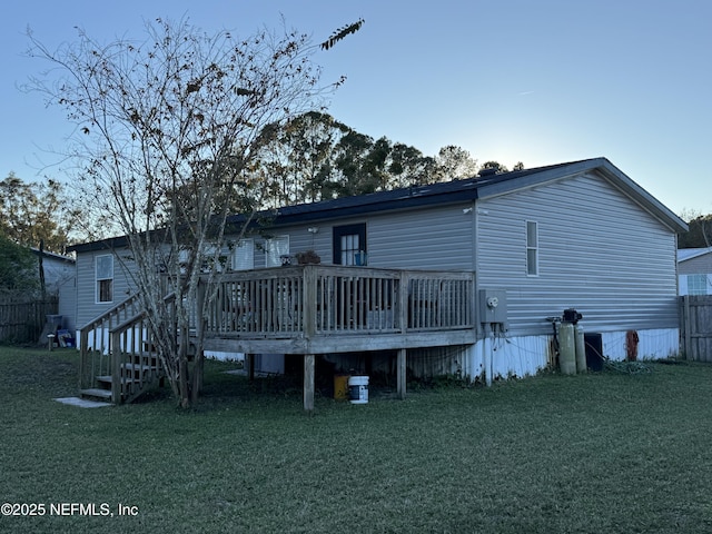 back of house featuring a lawn and a wooden deck