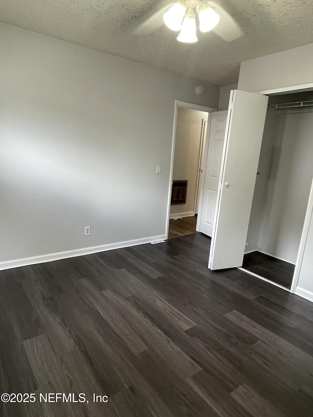 unfurnished bedroom featuring a textured ceiling, a closet, ceiling fan, and dark wood-type flooring