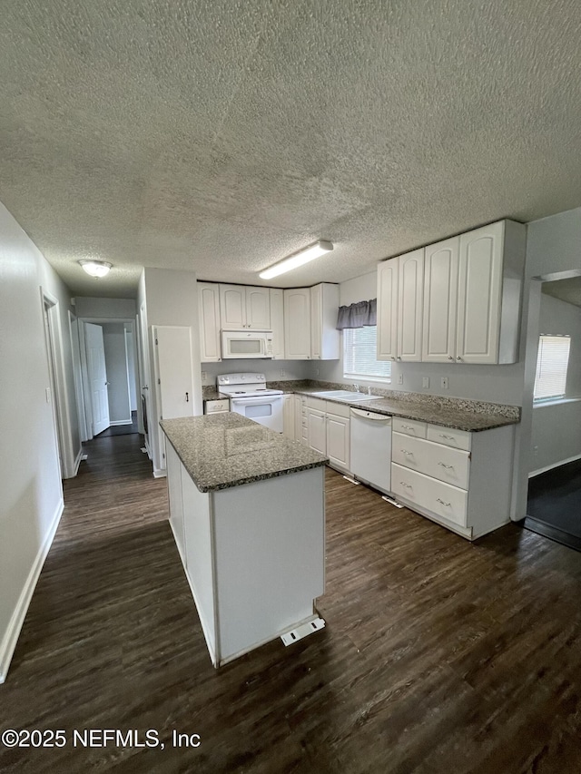 kitchen with white cabinets, white appliances, dark hardwood / wood-style floors, and a kitchen island