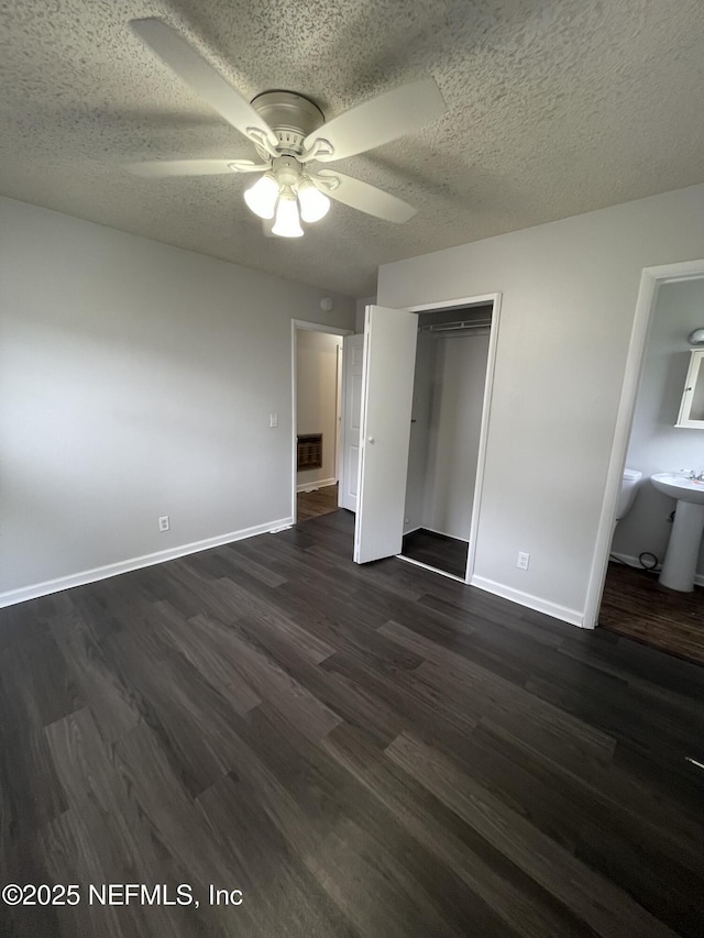 unfurnished bedroom featuring dark hardwood / wood-style flooring, a closet, ceiling fan, and connected bathroom