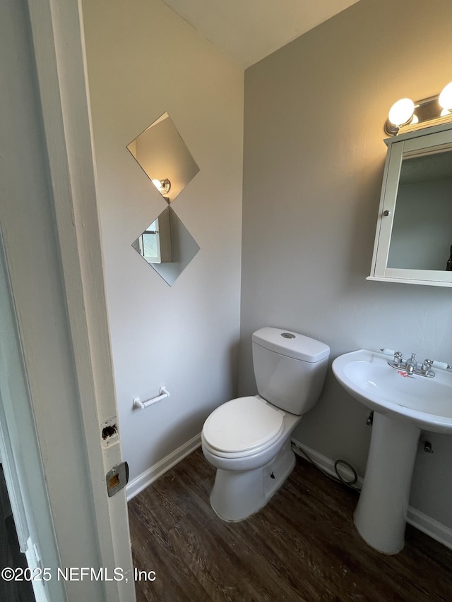 bathroom with wood-type flooring, toilet, and sink