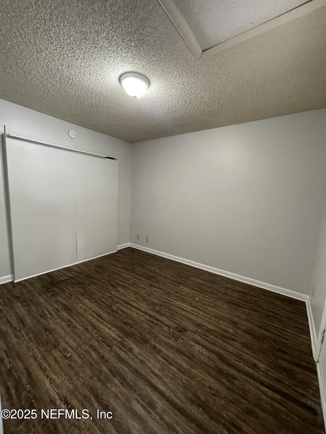 unfurnished room with a textured ceiling and dark wood-type flooring