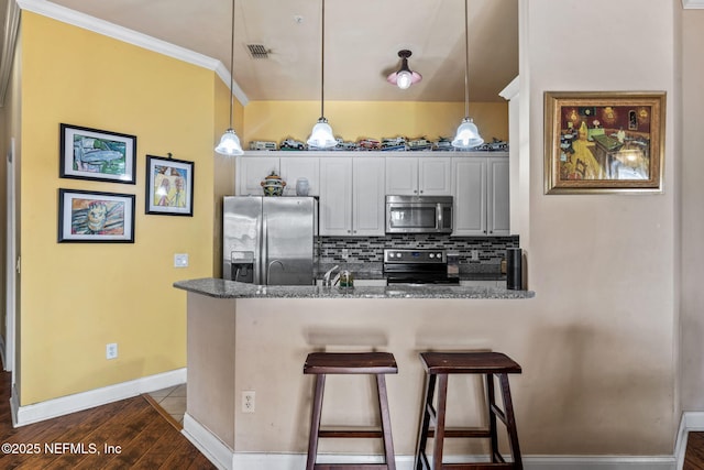 kitchen featuring stainless steel appliances, decorative light fixtures, kitchen peninsula, and dark stone countertops