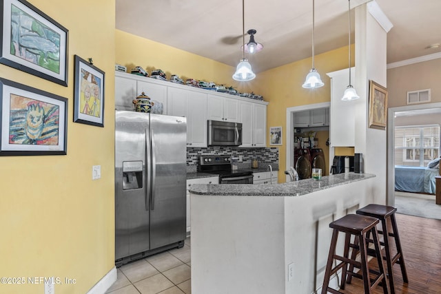 kitchen with a breakfast bar, white cabinetry, kitchen peninsula, pendant lighting, and stainless steel appliances