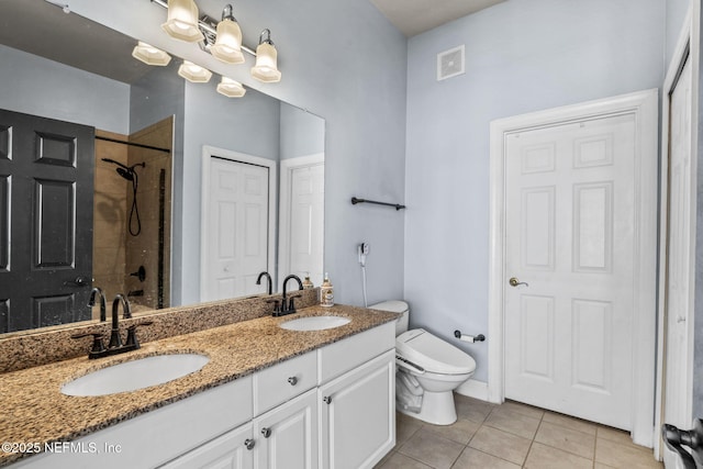 bathroom featuring vanity, a tile shower, tile patterned floors, and toilet