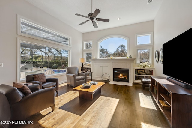 living room with ceiling fan, dark hardwood / wood-style flooring, and a high ceiling