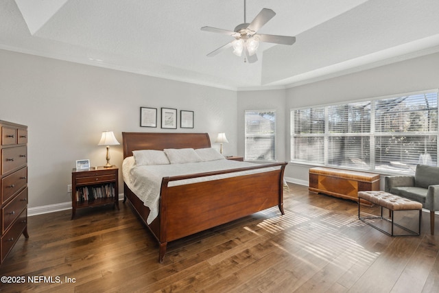 bedroom with dark hardwood / wood-style flooring, ornamental molding, ceiling fan, and a tray ceiling