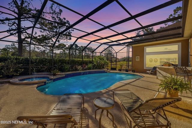 pool at dusk with an in ground hot tub, a lanai, and a patio area