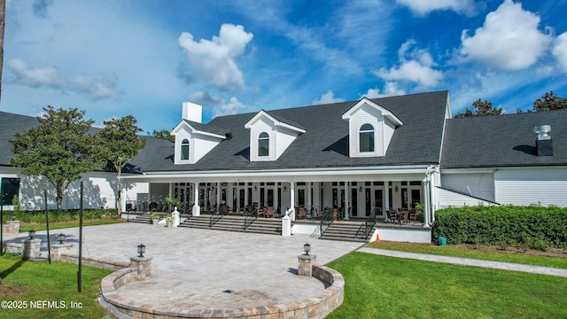 cape cod-style house featuring a front yard and a patio area