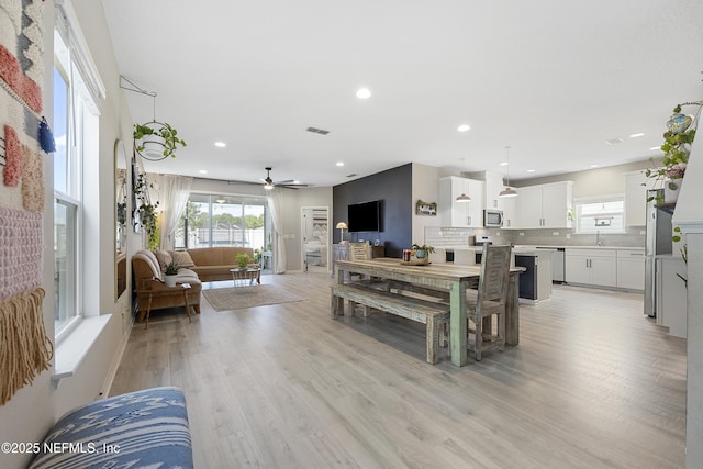 dining room with ceiling fan, light hardwood / wood-style floors, and sink