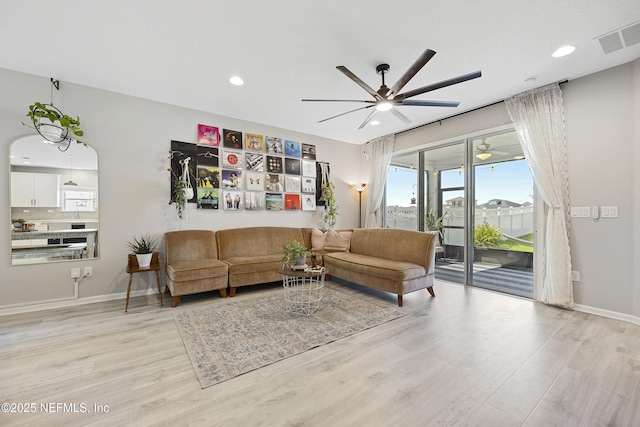 living room with ceiling fan and light hardwood / wood-style flooring