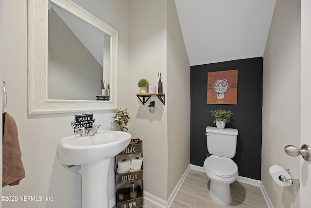 bathroom with toilet, wood-type flooring, vaulted ceiling, and sink