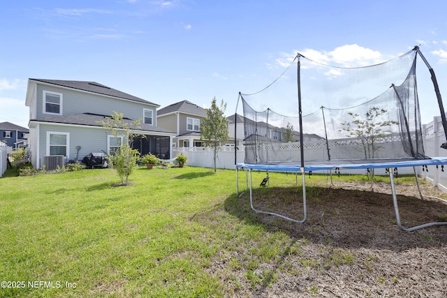 view of yard featuring a trampoline, cooling unit, and a sunroom