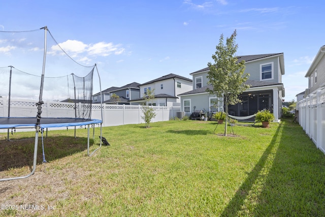 view of yard featuring a sunroom and a trampoline