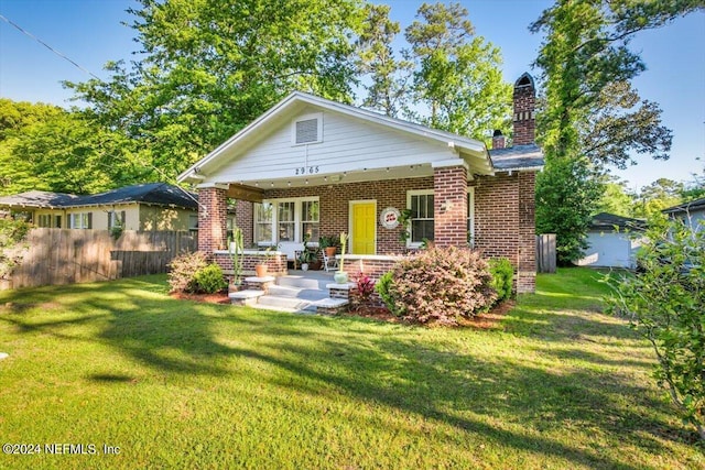 back of property featuring a lawn and covered porch