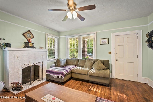 living room featuring a textured ceiling, a brick fireplace, ceiling fan, and dark wood-type flooring