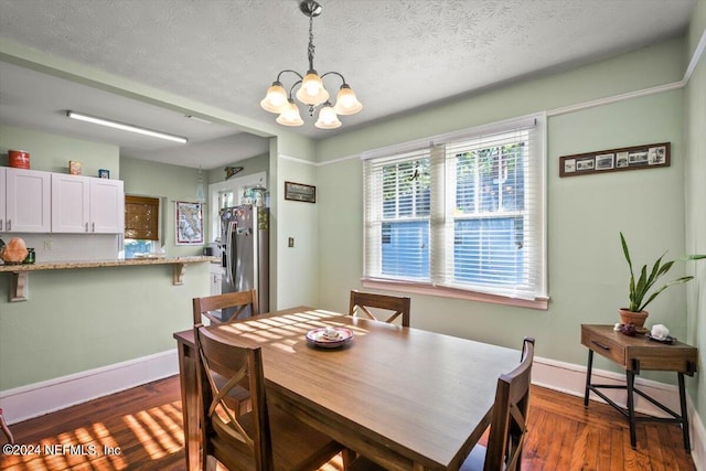 dining room featuring a textured ceiling, dark wood-type flooring, and a chandelier