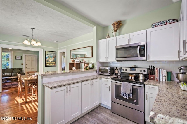 kitchen with kitchen peninsula, white cabinetry, light hardwood / wood-style floors, and appliances with stainless steel finishes