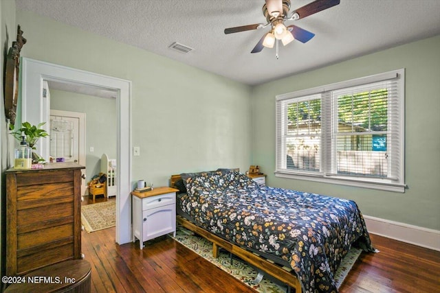 bedroom with a textured ceiling, ceiling fan, and dark wood-type flooring