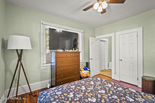 bedroom featuring ceiling fan, hardwood / wood-style floors, and a textured ceiling