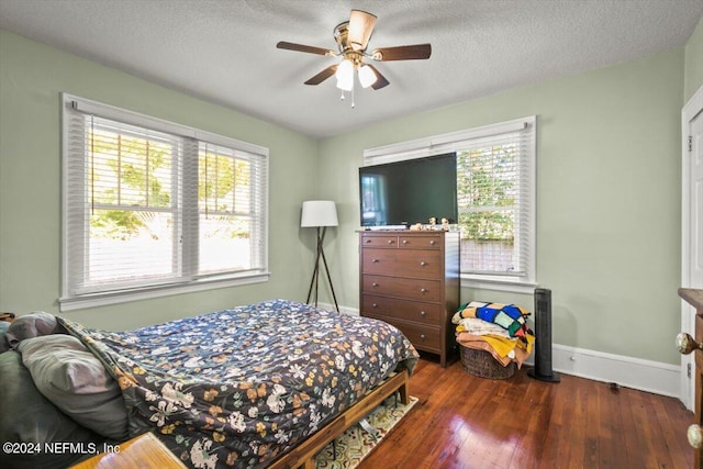 bedroom featuring multiple windows, ceiling fan, dark wood-type flooring, and a textured ceiling