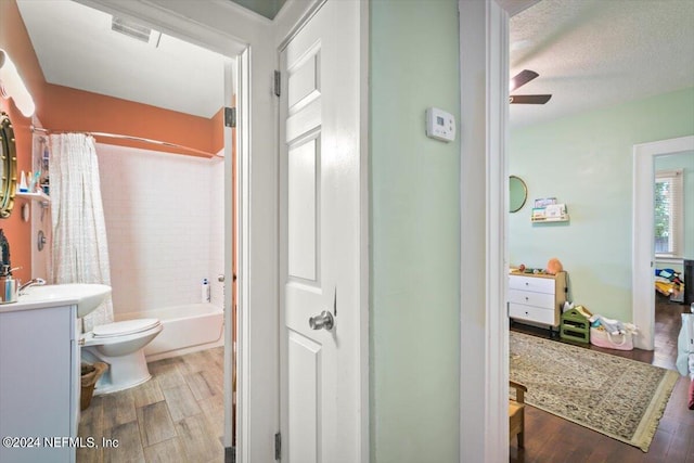 full bathroom featuring vanity, a textured ceiling, shower / bathtub combination with curtain, hardwood / wood-style floors, and toilet