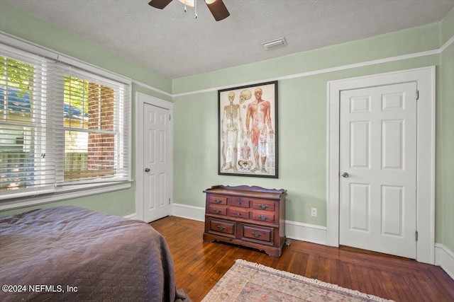 bedroom with ceiling fan, dark wood-type flooring, and a textured ceiling