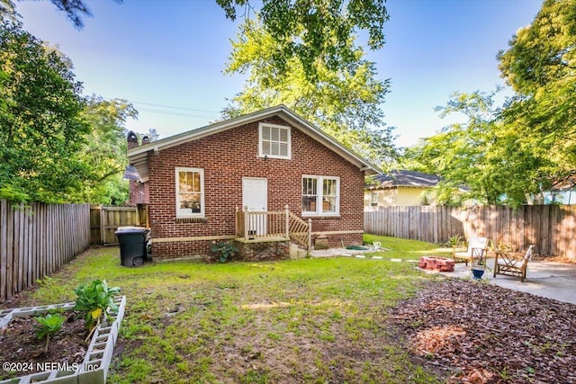 back of property featuring a patio area, a yard, and a fire pit