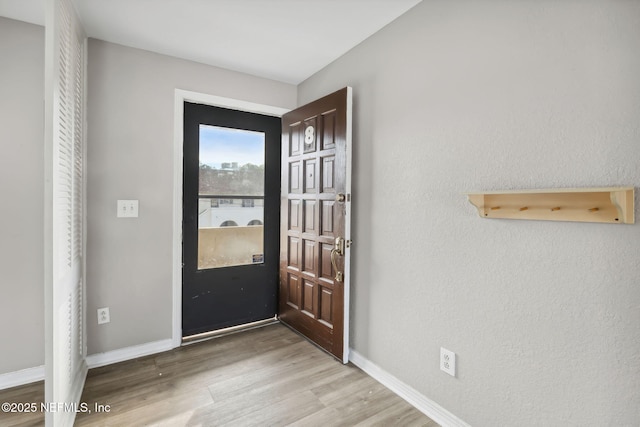 foyer entrance featuring light wood-style flooring and baseboards