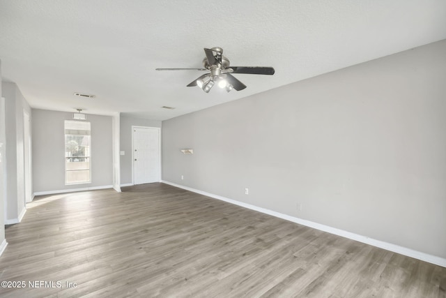 spare room with visible vents, ceiling fan, a textured ceiling, wood finished floors, and baseboards