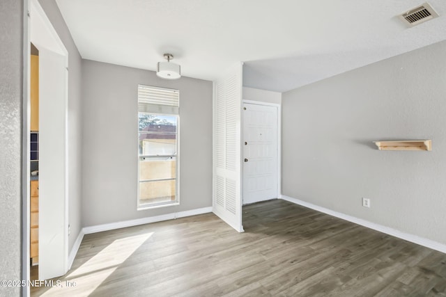 interior space with baseboards, visible vents, and wood finished floors