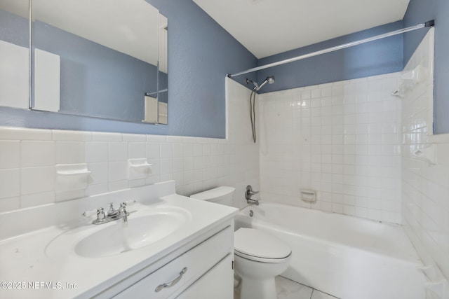 bathroom with wainscoting, toilet, shower / tub combination, vanity, and tile walls